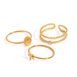 Detail view of gold ocean ring set featuring starfish and shell charms with zircons