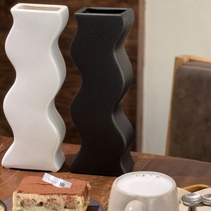Vasi moderni in ceramica ondulata bianco e nero su un ripiano in legno naturale