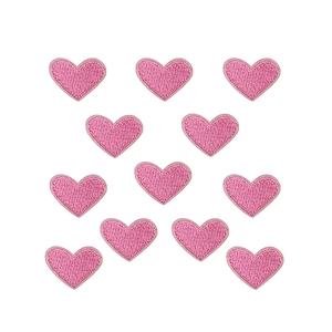Macro shot of 10 pink embroidered heart patches with detailed stitching on white background