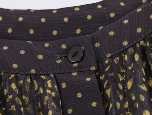 Detail of dark blue polka dot fabric with black buttons and fine pleated craftsmanship