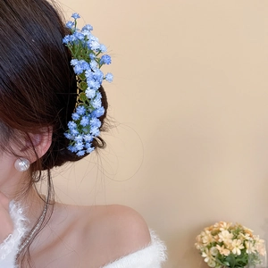 Detailed view of light blue baby's breath floral hair clip on model's hair
