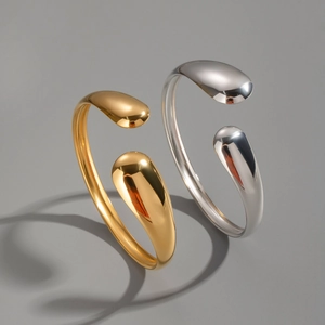Macro shot of gold and silver minimalist water drop open bangles with high-polished finish