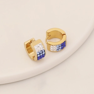Macro de boucles d'oreilles dorées avec strass dégradé bleu sur plateau céramique