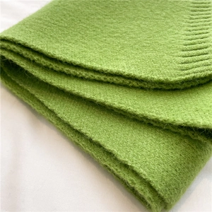 Close-up of soft green knitted scarf showing detailed fuzzy texture and warm fabric