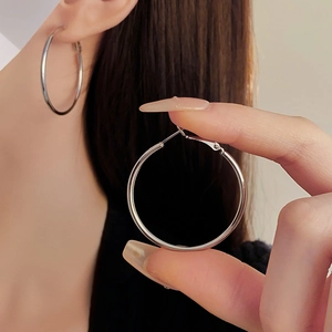 Detailed view of silver minimalist hoop earrings worn by a model in professional lighting