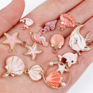 Pink marine life alloy charms set with starfish, seahorse and shells held in hand