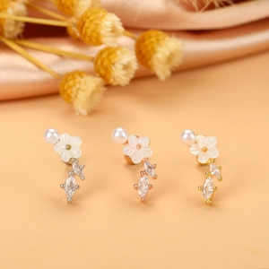 Détails macro des boucles d'oreilles fleur en argent, or rose et or avec zircons cubiques