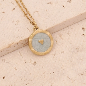 Macro view of a gold circular pendant featuring blue-grey enamel and a small heart detail