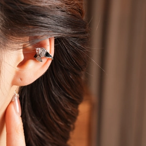 Detailed close-up of double-layered silver ear cuff with zircon and black enamel M-shape