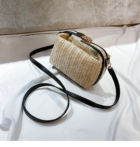 Detail view of straw woven bag with black leather trim and golden metal snap closure