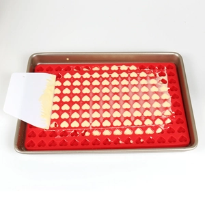 Spreading white cream into red heart silicone mold for chocolate and candy making