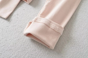 Detail of light pink baby knit cotton fabric with ribbed cuffs on gray texture