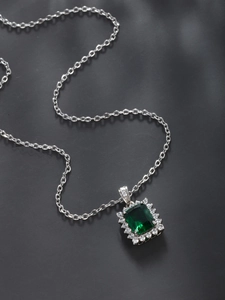 Macro shot of an elegant square emerald pendant necklace with a sparkling diamond halo