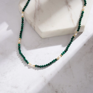 Detail of beaded necklace with green faceted malachite beads and natural white pearls