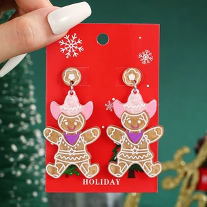 Close-up of acrylic gingerbread man earrings with pink cowboy hat and holiday card