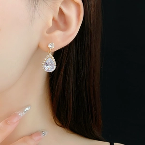 Gros plan d'élégantes boucles d'oreilles goutte dorées avec zircons clairs sur un modèle