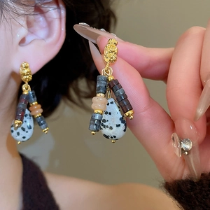 Detailed close-up of bohemian drop earrings with gold finish and natural stones