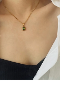 Detail of emerald green gemstone pendant necklace on model with white shirt and black strap