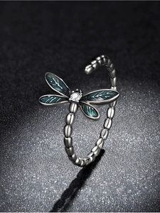 Macro detail of silver dragonfly ring with green enamel wings and zircon stone