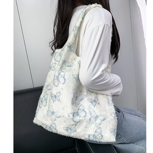 Détail du cabas en toile blanche avec broderie papillon bleue et bords effilochés