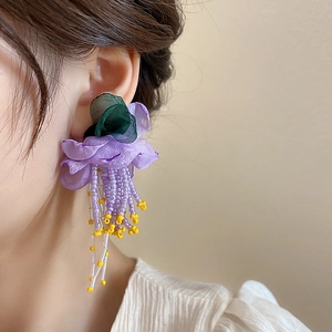 Gros plan détaillé sur des boucles d'oreilles fleurs en tulle violet à glands de perles
