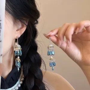 Détail de boucles d'oreilles vintage en argent avec perles goutte bleu paon et design floral