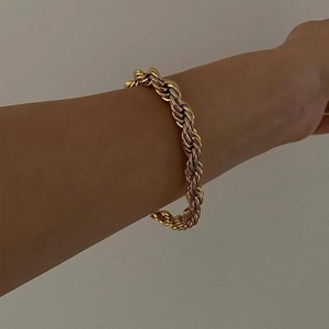 Nahaufnahme eines vergoldeten Kordelketten-Armbands am Handgelenk mit Metallstruktur
