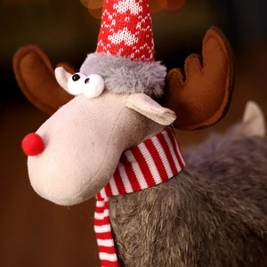 Close-up of a Christmas reindeer plush with warm bokeh background and festive red scarf