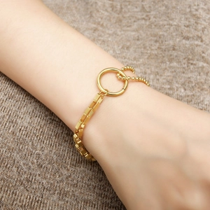 Detailed close-up of a gold-plated stainless steel chain bracelet on a soft knit background