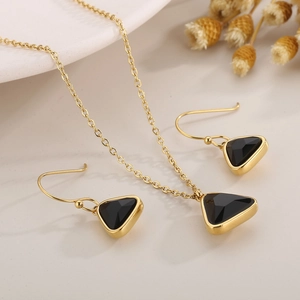 Detailed view of golden triangular necklace and earrings set with black crystals