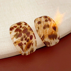 Detailed close-up of square leopard print acrylic earrings on a neutral fabric background