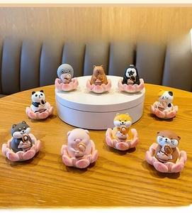 Détail de figurines d'animaux en résine mignonnes sur des fleurs de lotus, idéal pour déco de bureau.