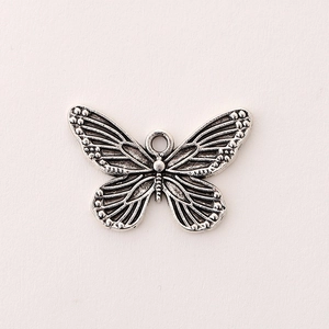 Macro detail of a silver zinc alloy butterfly pendant with textured wings for DIY jewelry