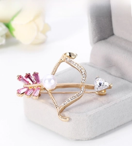 Macro shot of Cupid arrow brooch with heart zircon and pink crystals on velvet box