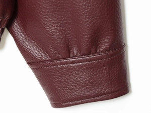 Macro shot of burgundy faux leather sleeve cuff showing detailed lychee grain texture