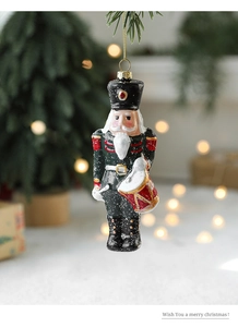 Detail of nutcracker drummer ornament with glitter snowflakes hanging on Christmas tree branch
