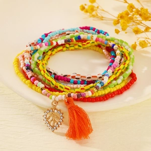 Detail of bohemian layered seed bead anklets with orange tassel and leaf charms