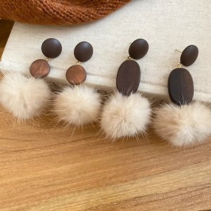 Detail of vintage wooden stud earrings with soft fur pom poms for autumn winter style