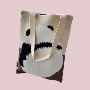 Close-up of knit tote bag detail with panda pattern and a small brand tag on the side