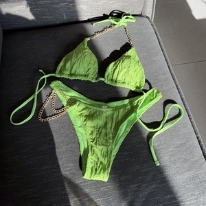 Neon green bikini set with gold chain straps and textured fabric in a flat lay view