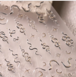 Macro view of 3D silver snake nail stickers with metallic moon and star patterns