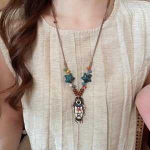 Detailed close-up of ceramic fish pendant with starfish beads on ethnic necklace