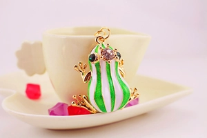 Macro shot of green and white frog charm with sparkling crystals and golden edges
