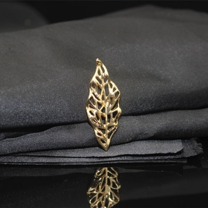 Macro detail of golden hollow leaf charm for DIY hair accessories on black satin