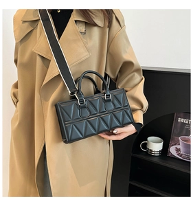 Detail of black triangular embossed faux leather handbag with contrast wide shoulder strap
