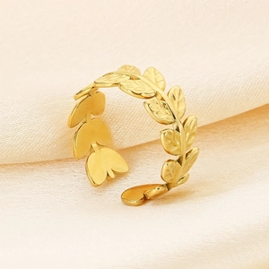 Close-up of gold leaf-shaped open ring on beige silk background with detailed texture