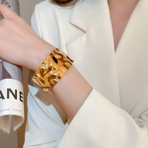 Detail of wide gold cuff bracelet with irregular hammered texture on model