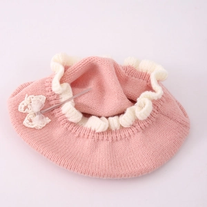 Pink knit beret for baby girls with white ruffled edges and a delicate lace bow
