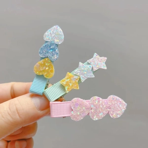 Close-up of glitter resin heart and star hair clips with colorful ribbon-wrapped metal bases