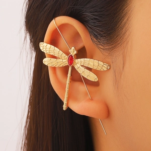 Gros plan d'un earcuff libellule dorée avec pierre rouge et ailes aux détails fins